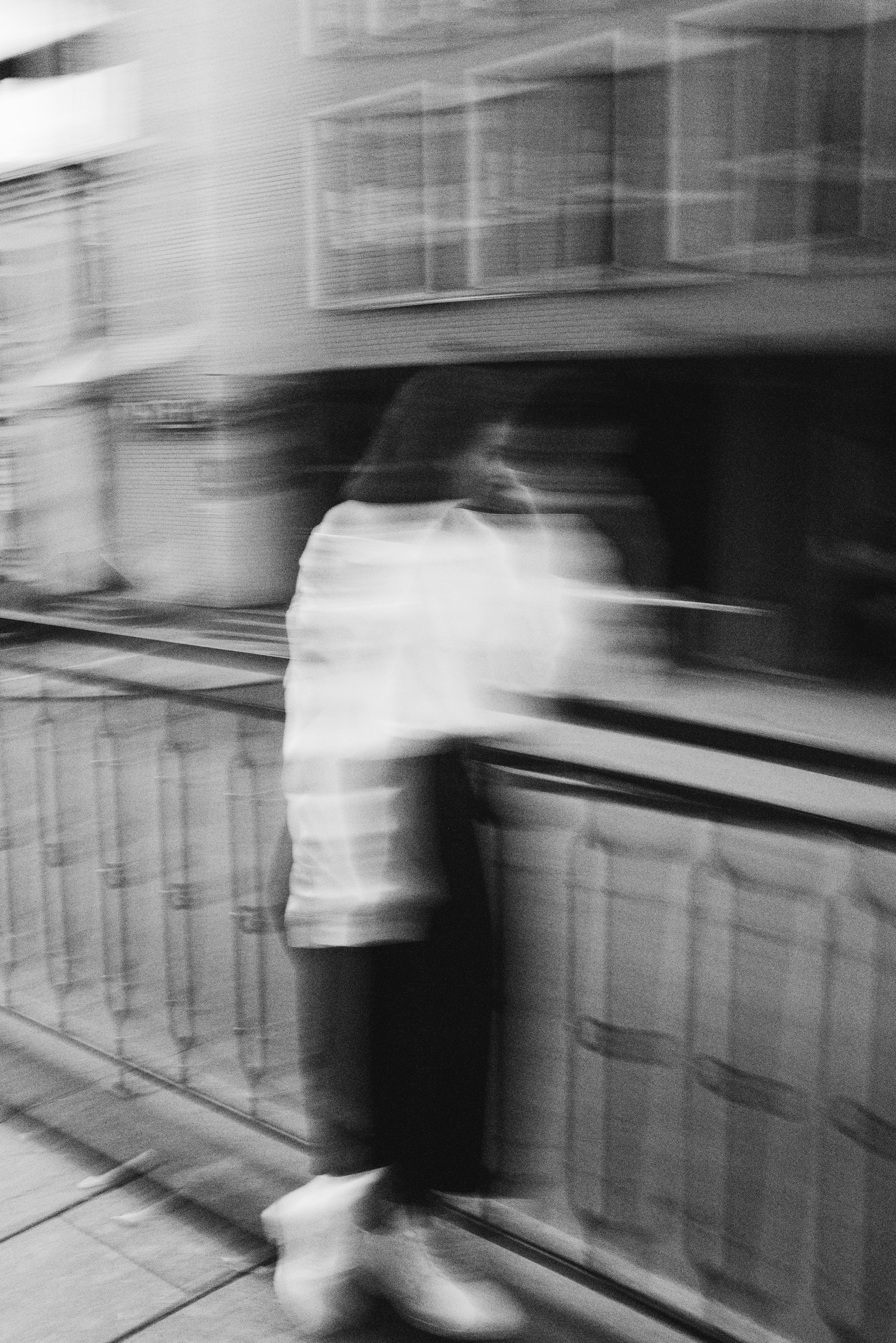 grayscale photo of man in white dress shirt and black pants standing on train station